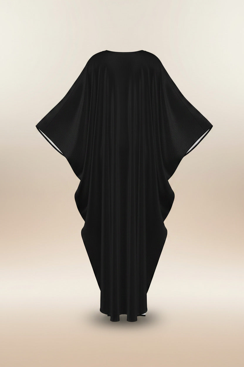 A black draped kaftan dress with wide, flowing sleeves and a high-low hemline, shown against a plain white background.