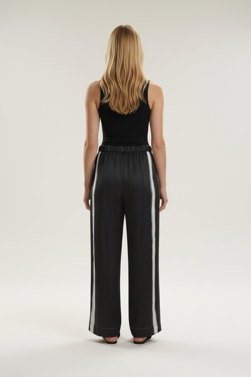 Back view of a model wearing the NIMIAN Nocturna striped silk pyjama trousers