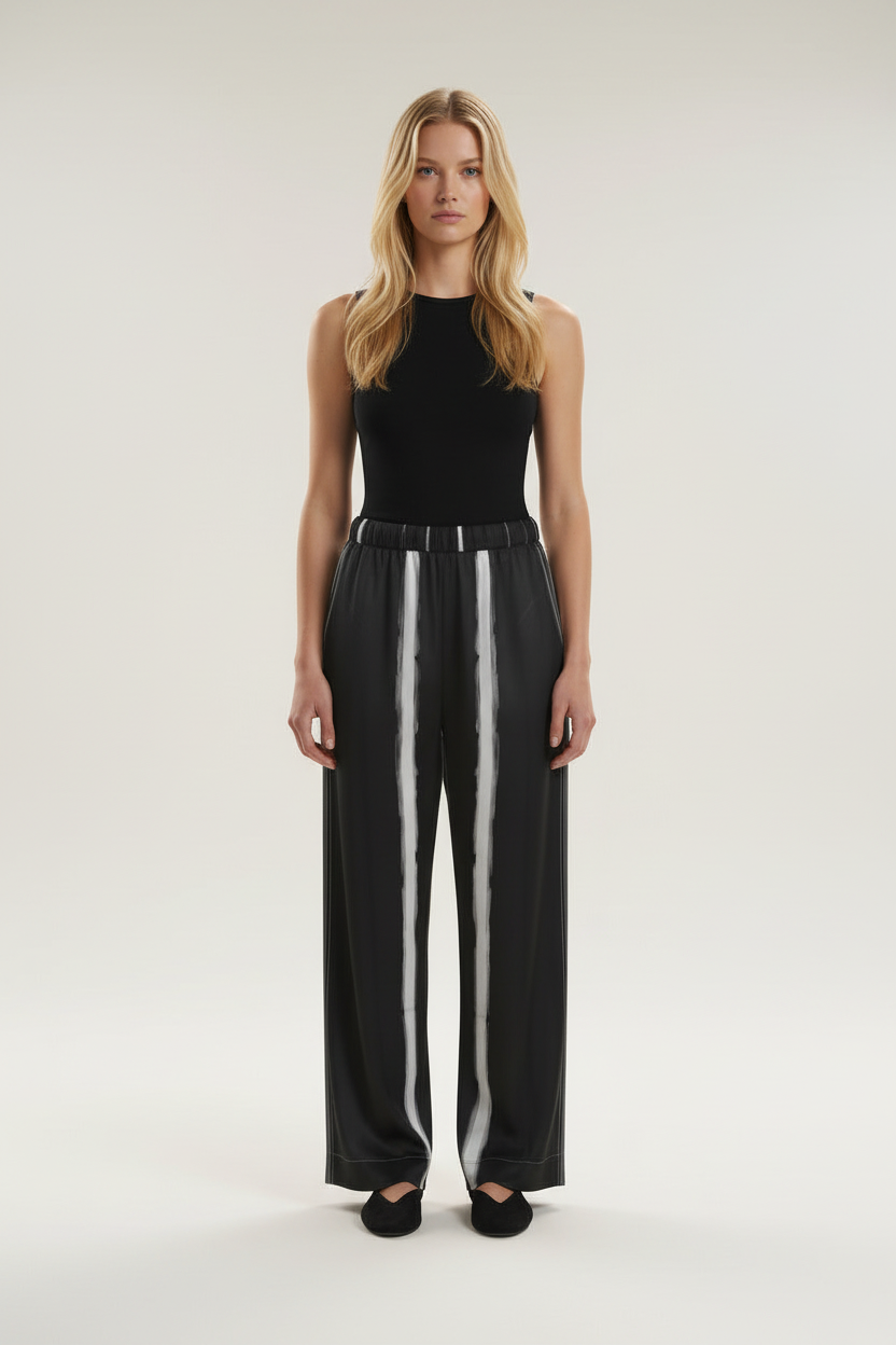 Front view of a model wearing the NIMIAN Nocturna striped silk pyjama trousers