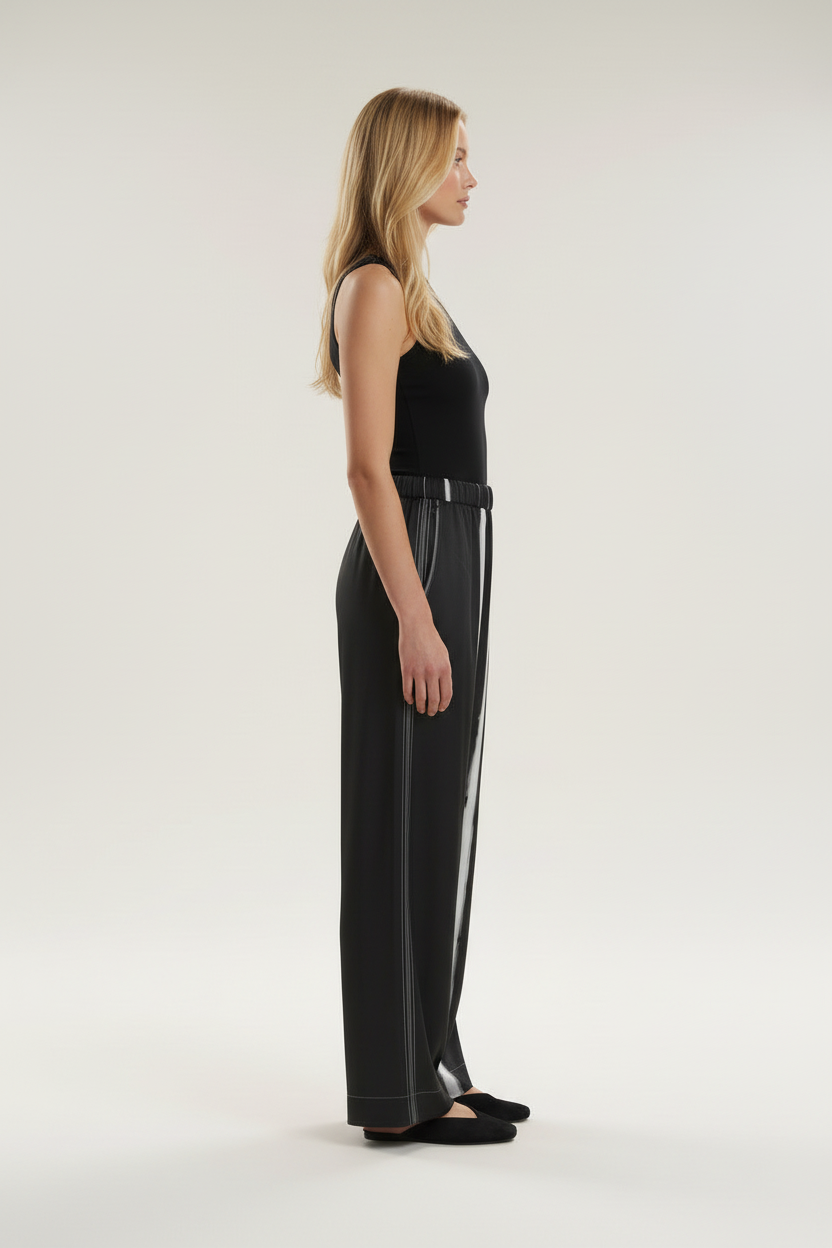 Side view of a model wearing the NIMIAN Nocturna striped silk pyjama trousers